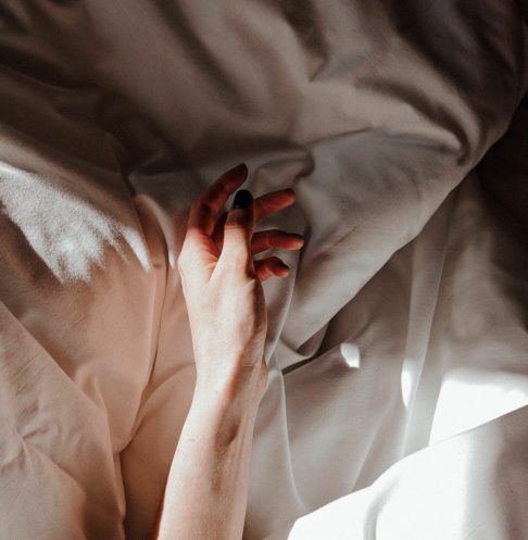 person resting hand on chest calm bed